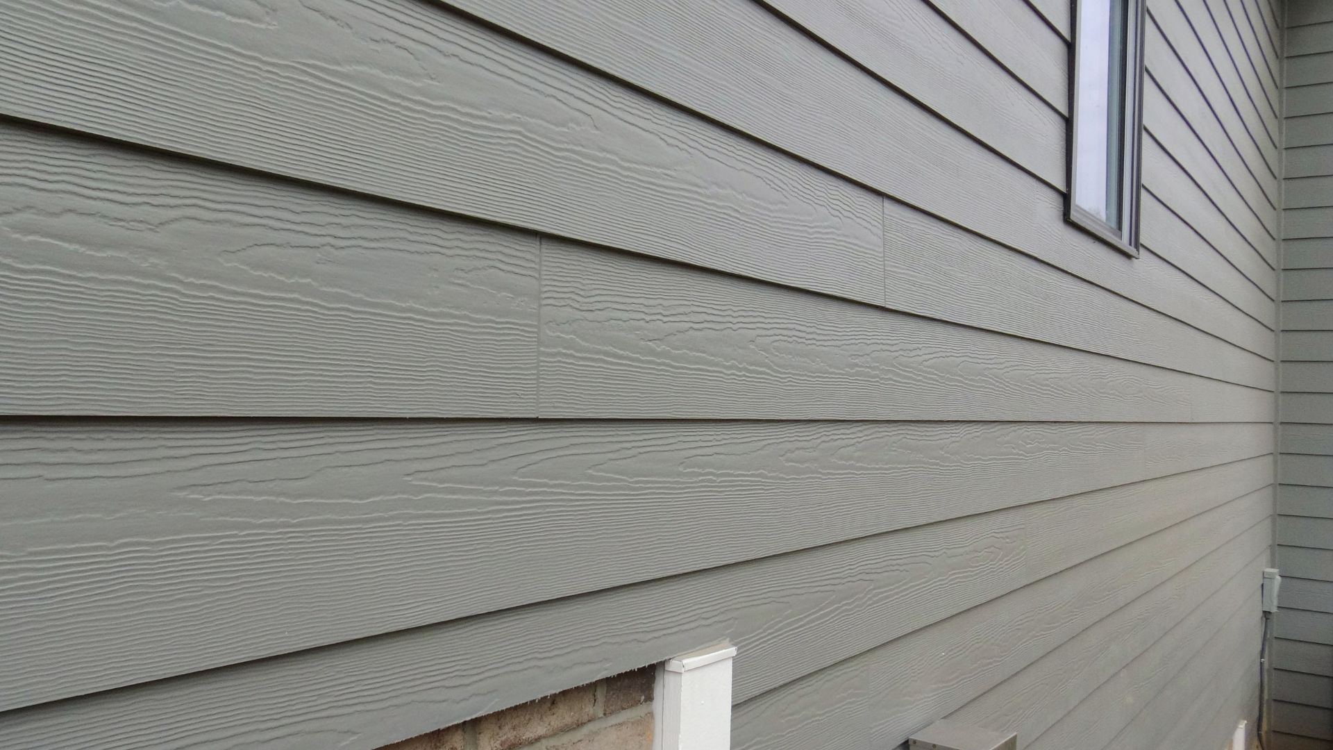 Gray horizontal siding on house exterior with wood-like texture and window