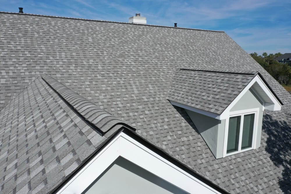 Gray shingle roof with multiple angles and a white dormer window