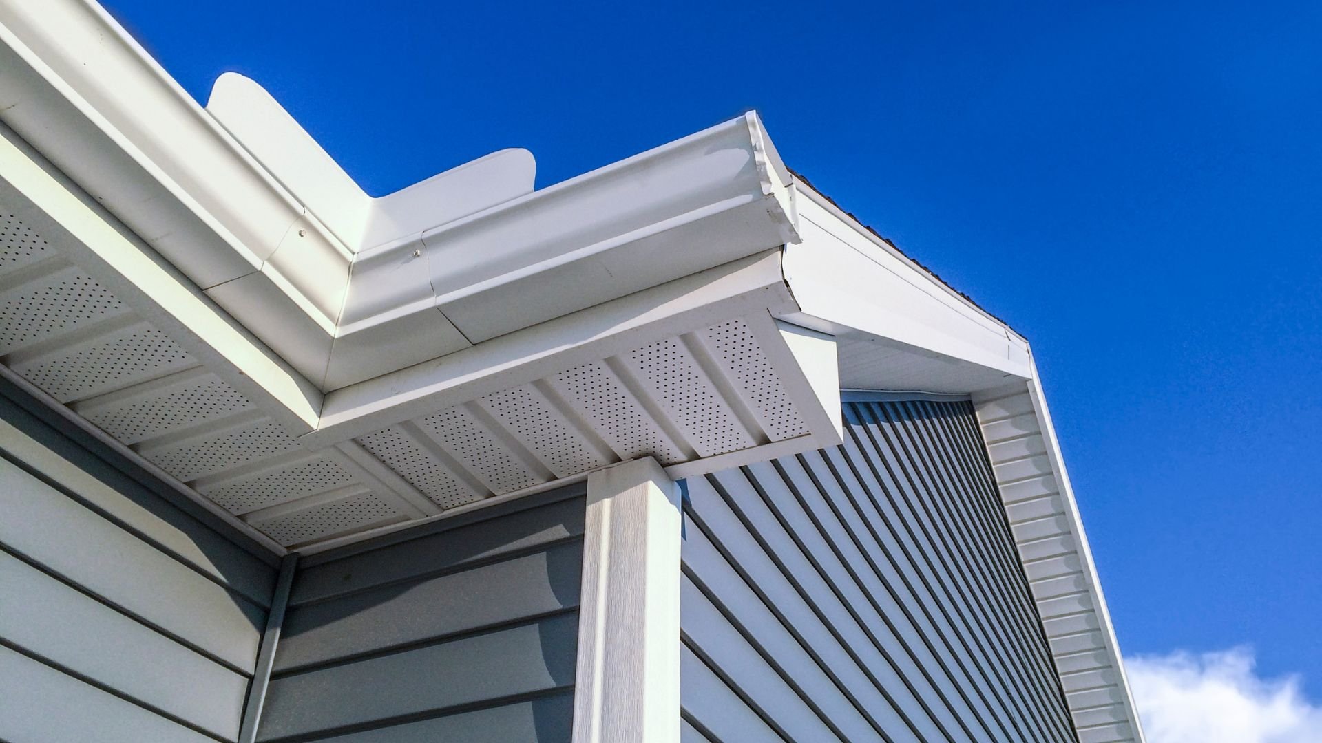 White modern building roof and siding detail against bright blue sky