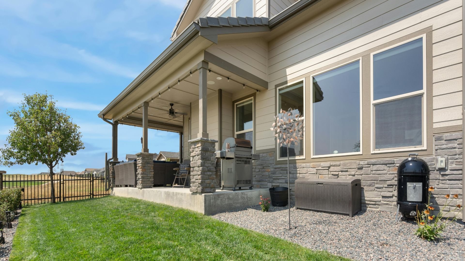 Modern home with covered patio, grill, and landscaped backyard